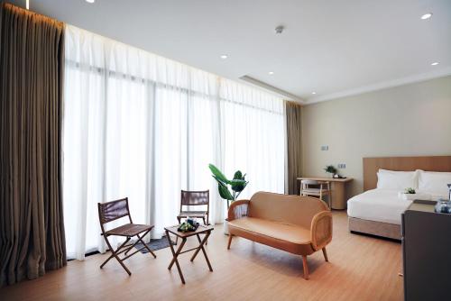 a hotel room with a bed and a couch and chairs at ALVILLA Kampung Cina in Kuala Terengganu