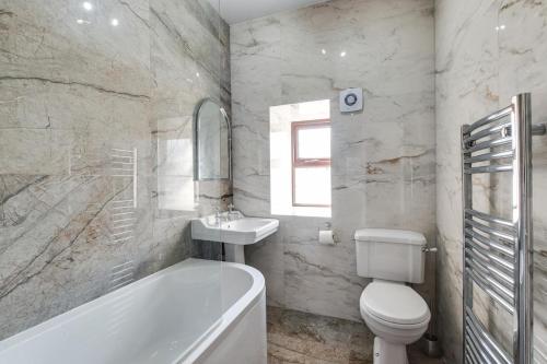 a bathroom with a tub and a toilet and a sink at 4 Bed in Buxton oc-dcjar in Tideswell
