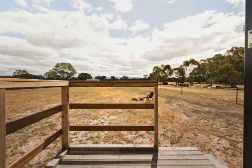 a fence in a field with a dog behind it at Bellellen Park 1 by Tiny Away in Stawell