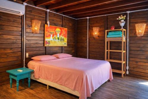 a bedroom with a bed and a painting on the wall at Vilarejo Hospedagem in Ilha do Mel