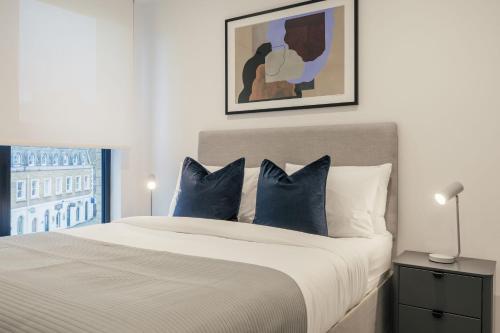 a bedroom with a large bed with blue pillows at Urban Rest Camden Town in London