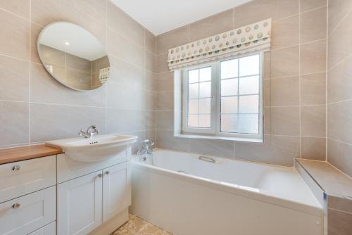 a bathroom with a sink and a tub and a mirror at 2 Bed in Beccles oc-rilo in Beccles