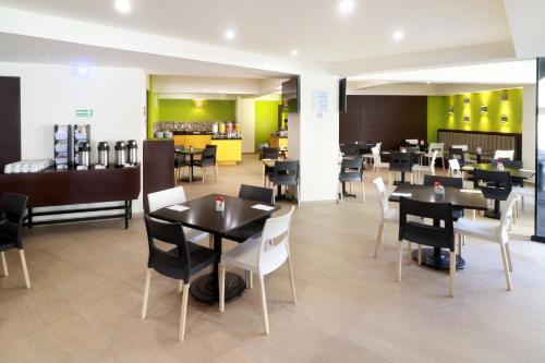 a restaurant with black tables and white chairs at Holiday Inn Express Mexico Aeropuerto by IHG in Mexico City