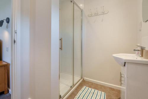 a white bathroom with a shower and a sink at 3 Bed in Staplecross oc-rh1162 in Sedlescombe
