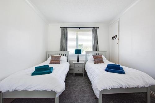 two beds in a room with white walls and a window at 3 Bed in Greatstone oc-ek777 in Littlestone-on-Sea