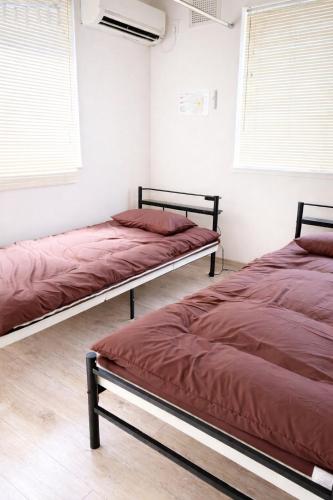 two beds sitting in a room with windows at シーシャイン北金沢 102号室 in Aomori