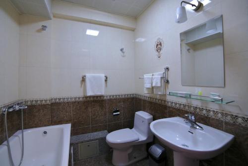 a bathroom with a sink and a toilet and a mirror at Tanan Center Serviced Apartments in Ulaanbaatar