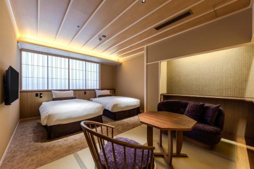 a hotel room with two beds and a table at Kyoto Ryokan SAKANOUE in Kyoto