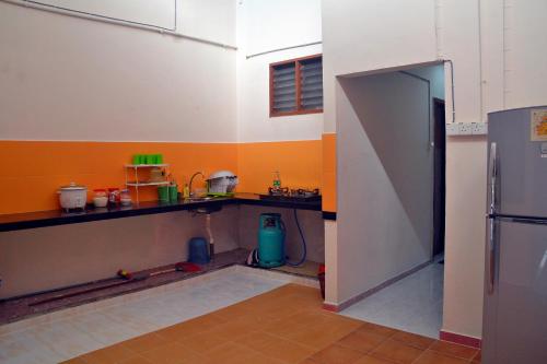a kitchen with a counter and a sink and a refrigerator at Homestay Kota Bharu, Telipot in Kota Bharu