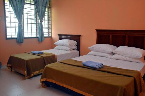 2 camas en una habitación con cortinas y ventanas azules en Homestay Kota Bharu, Telipot en Kota Bharu