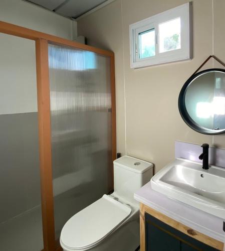 a bathroom with a toilet and a sink and a mirror at Chalaroste Place by SMS Hospitality in Bolinao