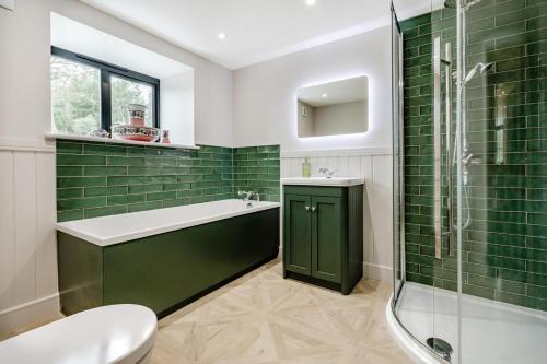 a bathroom with green tiles and a tub and shower at 5 Bed in Cyffylliog oc-c32596 in Cyffylliog
