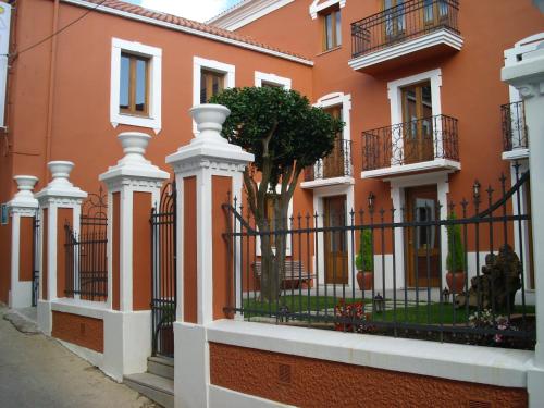 un edificio naranja con una valla y un árbol en Hotel Cabo Ortegal, en Cariño