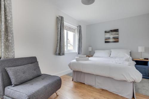 a white bedroom with a bed and a chair at 1 Bed in Seahouses oc-gd1735 in Seahouses