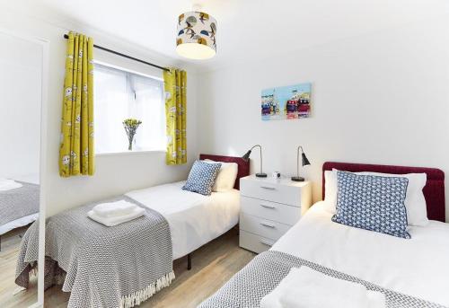 a bedroom with two beds and a window with yellow curtains at 2 Bed in St. Ives oc-p00693 in Carbis Bay