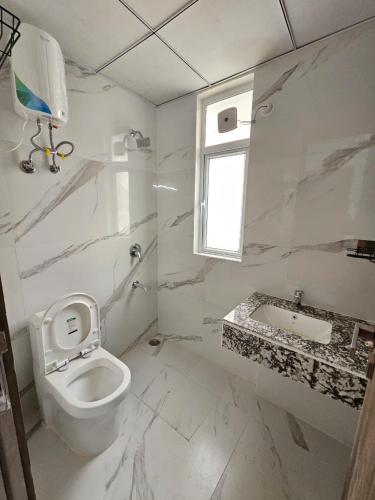 a white bathroom with a toilet and a sink at Cozy corner in Gurgaon
