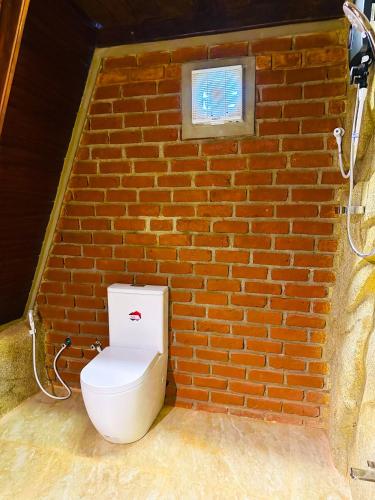 a toilet in front of a brick wall at The Classic Crown Sigiriya in Sigiriya