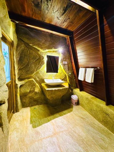 a stone bathroom with a sink in a stone wall at The Classic Crown Sigiriya in Sigiriya