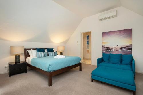 a bedroom with a bed and a blue chair at Apt 9 'Delphinius' @ Bay View Centro, Dunsborough in Dunsborough
