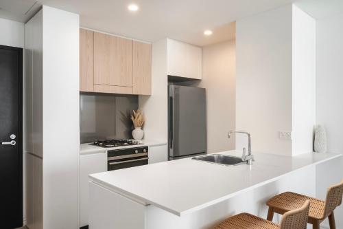 a white kitchen with a sink and a refrigerator at 1010 - Elite Escape - Absolute Beachfront Luxury in Newcastle