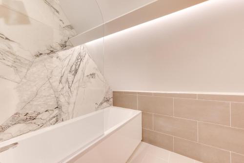 a bathroom with a white tub and a marble wall at 3 Bed in Arundel oc-bt007 in Arundel
