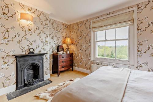 a bedroom with a fireplace and a bed and a window at 5 Bed in Sedlescombe oc-l27505 in Sedlescombe