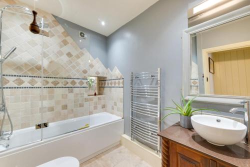 a bathroom with a tub and a sink and a bath tub at 3 Bed in Hope Valley oc-dcherb in Eyam