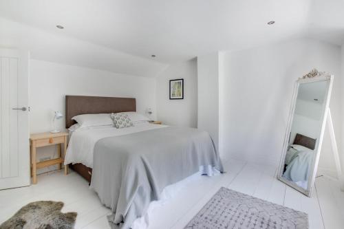 a white bedroom with a bed and a mirror at 2 Bed in Breage oc-jobcot in Breage