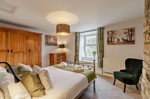 a bedroom with a bed and a chair and a window at 4 Bed in Arkengarthdale oc-h27492 in Low Eskcleth
