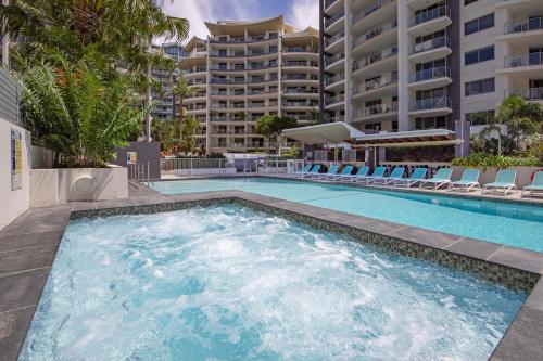 a swimming pool with chairs and a building at Trilogy Surfers Paradise in Gold Coast