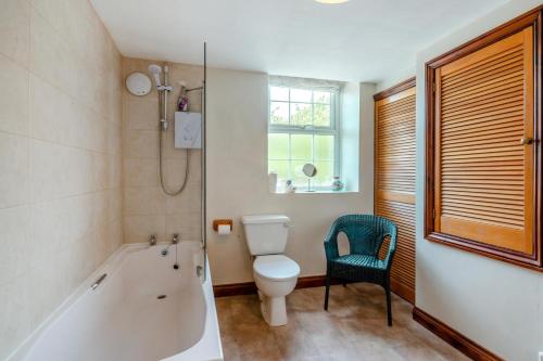 a bathroom with a tub and a toilet and a chair at 3 Bed in Carperby oc-e30625 in Carperby