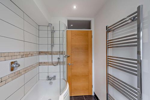 a bathroom with a tub and a wooden door at 3 Bed in Aberdovey oc-n29124 in Aberdyfi
