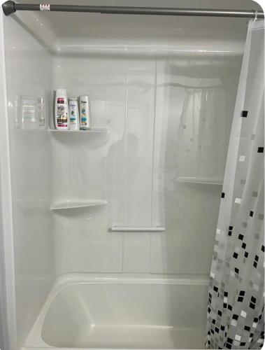 a white bathroom with a shower with a tub at Cozynest in Moncton