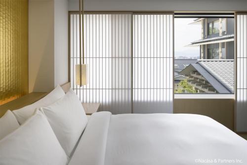 a bedroom with a white bed and a large window at Banyan Tree Higashiyama Kyoto in Kyoto