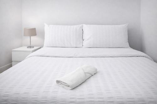 a white bed with a towel laying on it at 4-Bed House in Enfield- Sleeps 8- Private garden in Enfield