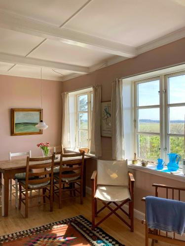 a dining room with a table and chairs and windows at Charming Farmhouse With Views On Møn in Borre