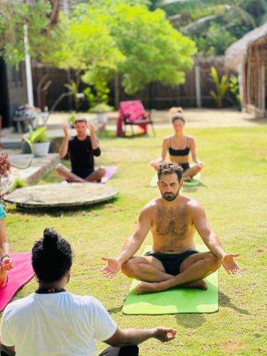 a group of people doing yoga in the grass at Kiteclub in Kalpitiya