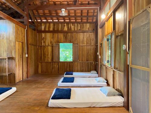 three beds in a room with wooden walls at Nui Tuong Village Stay in Tân Phú