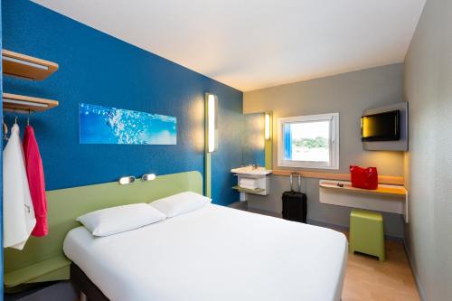a bedroom with a white bed and a blue wall at Ibis Budget Angers Parc des Expositions in Saint-Sylvain-dʼAnjou