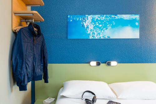1 dormitorio con 2 camas y pared azul en Ibis Budget Angers Parc des Expositions en Saint-Sylvain-dʼAnjou