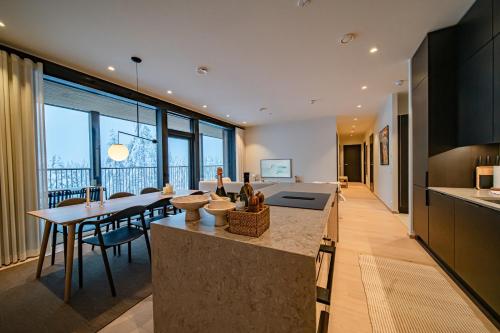a kitchen and living room with a table and chairs at Fjällen Aurora Luxe Chalet Ski-in Ski-out by Aavalevi in Levi