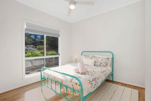 a white bedroom with a bed and a window at Beach by the Dunes in Goolwa South