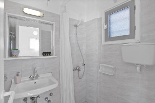 un baño blanco con lavabo y ducha en Seample studios, en Chrissi Akti