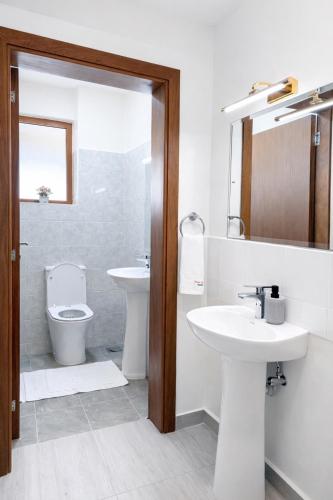 a white bathroom with a sink and a toilet at Shawmut Executive Suites With Heated Pool, GYM, Secure Parking, Full Power Backup in Nakuru