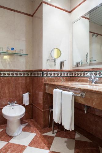a bathroom with a sink and a toilet and a mirror at Hotel Cervantes in Seville