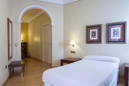 a bedroom with a white bed and an archway at Hotel Cervantes in Seville