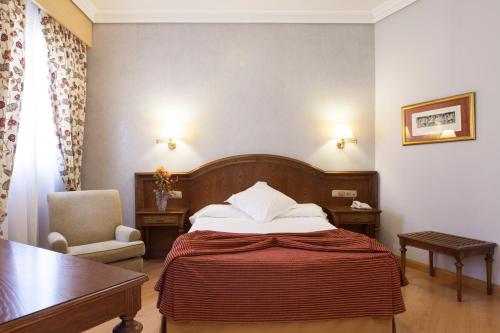 a hotel room with two beds and a lamp at Hotel Cervantes in Seville