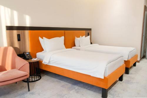 two beds in a hotel room with a chair at Afrosiyob Regency Hotel in Tashkent