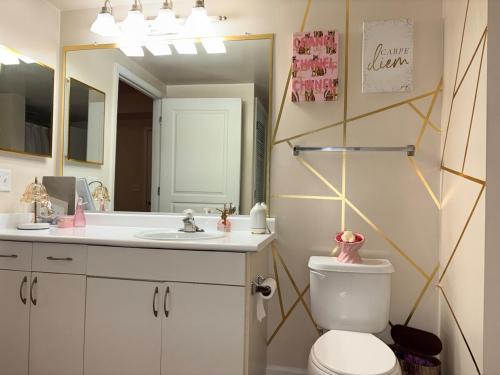 a bathroom with a toilet and a sink and a mirror at Luxury, Chic, Apt with Game Room, Movie Theatre, & 24hr Gym in Rockville