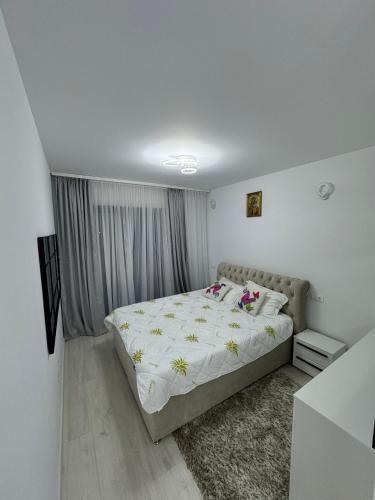 a white bedroom with a bed with flowers on it at Apartment in Ploiești 5 in Ploieşti